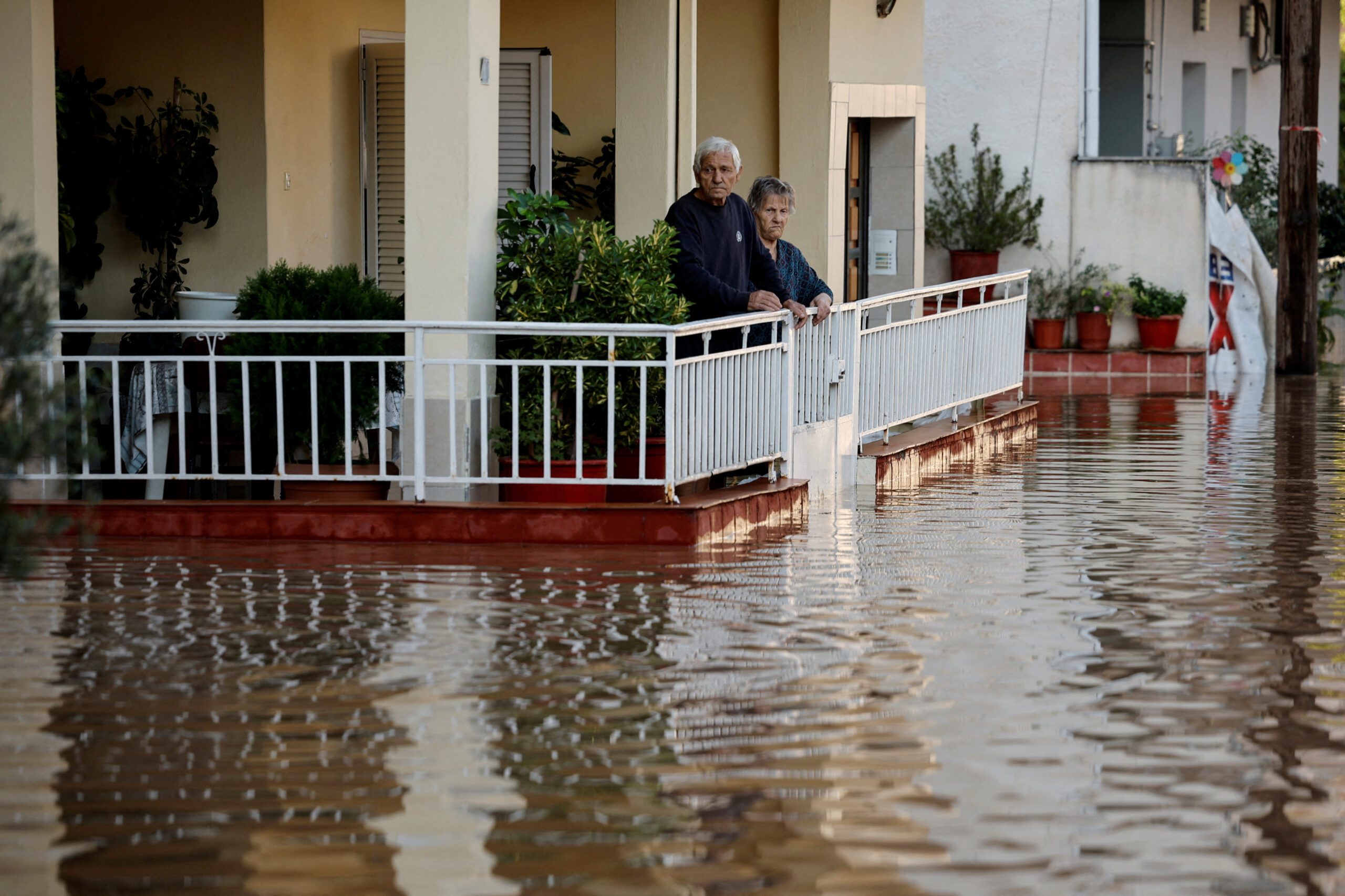 An elderly couple  look from their partially flooded house, as the Pinios river over flooded after torrential rains in Larissa, Greece September 8, 2023.  REUTERS/Louisa Gouliamaki